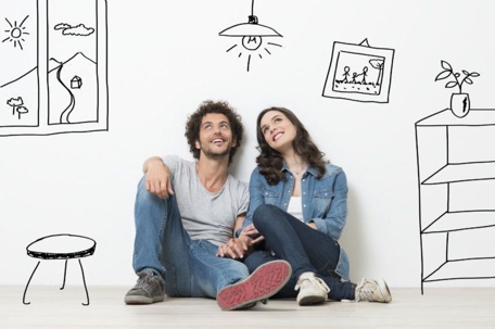 Couple sitting on floor of empty home imagining what it will look like once it's furnished.
