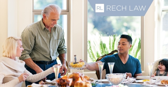 Group of people sitting at table passing food around.