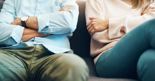 Couple sitting beside each other with arms crossed