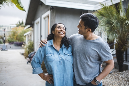 couple laughing outside of their house
