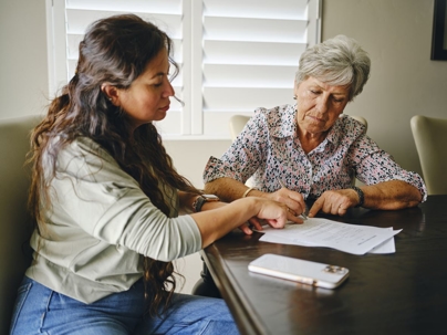 Woman signing power of attorney to daughter