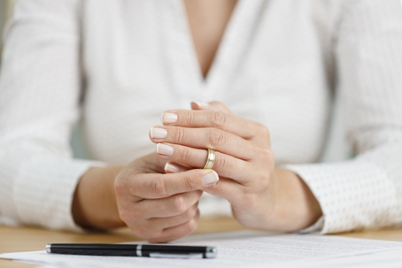 woman signing documents and removing wedding ring