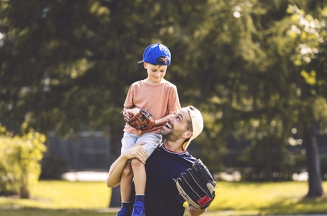 father and son playing baseball in a park