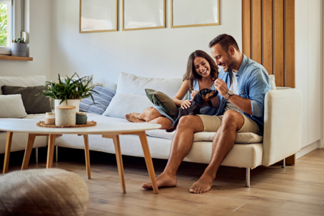 happy couple sitting on the couch with their dog