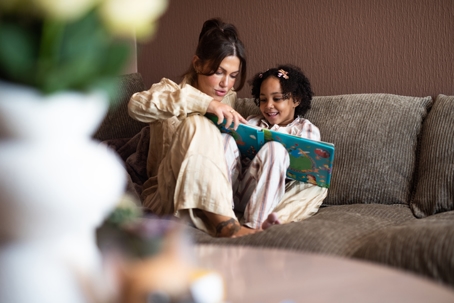 mother and daughter reading a book on the couch
