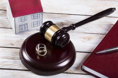 Two wedding rings sitting next to a judge's gavel, a book, and a toy house.