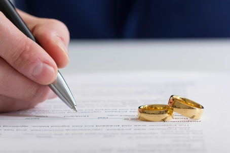 signing divorce decree with two wedding rings