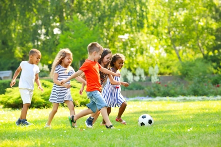 Cute little children playing soccer outdoors