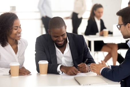 Man with woman sitting at table signing paperwork.