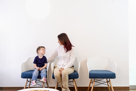 A boy child in doctors waiting room - reception with his mom.